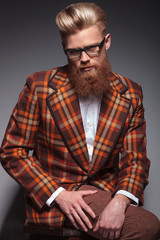 Obraz premium dramatic fashion model with long beard and glasses sitting