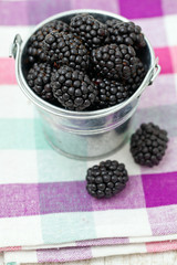 blackberries in a bucket on kitchen towel