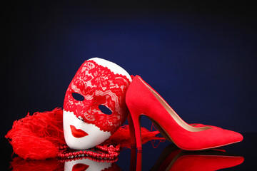 Beautiful red female shoes and carnival mask, on blue