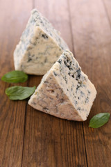 Tasty blue cheese with basil, on wooden table