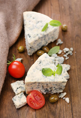 Tasty blue cheese with tomato, olives and basil, on wooden