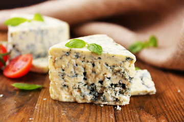 Tasty blue cheese with basil and tomato, on wooden table