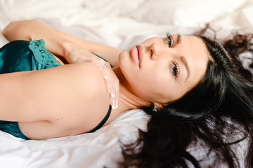 woman in pretty turquoise silk shirt on bed