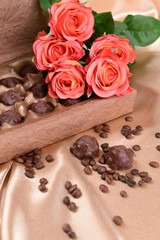 Delicious chocolates in box with flowers on gold background