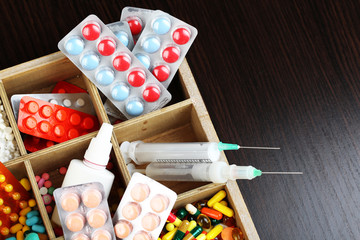 Medical pills, ampules in wooden box, on color wooden