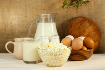 Tasty dairy products on wooden table, on sacking background