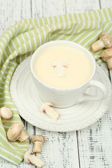 Delicate mushroom sauce in cup on wooden table close-up