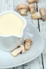 Delicate mushroom sauce in pitcher on wooden table close-up