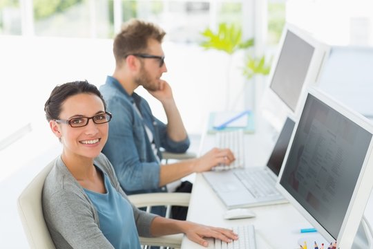 Team of young designers working at desk with woman smiling at