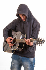 Sad teenager in hoodie playing acoustic guitar. Trying to write