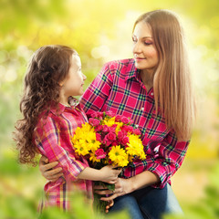 Daughter hugging his mother and gives her flowers