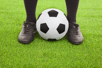Soccer player's feet with ball  on an open playing field