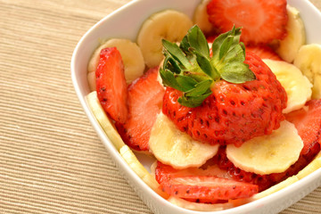 Sliced ​​banana and strawberries in a white bowl
