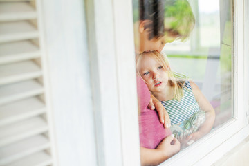 Mother and daughter looking through the window