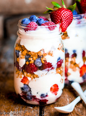 Granola Parfait with yogurt and berries on rustic background