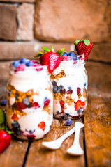 Granola Parfait with yogurt and berries on rustic background