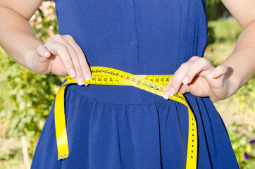 woman measuring waistline with centimeter