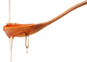 Honey dripping from a wooden honey dipper isolated on white back