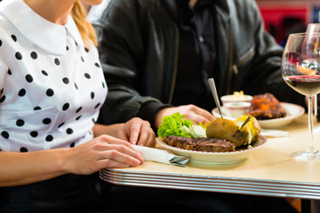Friends or couple eating and drinking in fast food diner