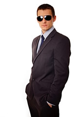 Young businessman at sunglasses standing, with hands in pockets