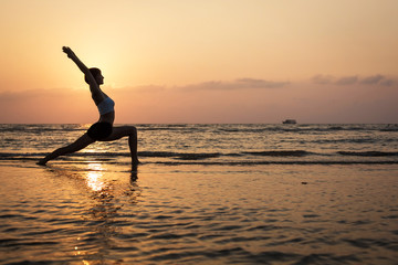 Fototapeta premium Yoga silhouette on the beach, virabhadrasana pose