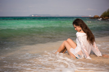 Fototapeta na wymiar Beautiful girl sitting in a waves on the beach .Feb 27, 2014