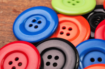 Colorful plastic buttons on a wooden surface