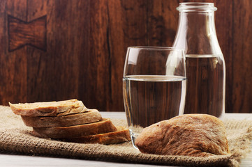 A glass bottle and a glass with water and sliced bread