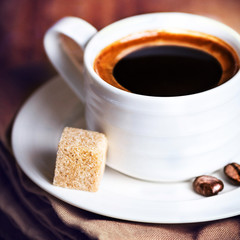Coffee cup with white saucer and roasted coffee beans  on wooden