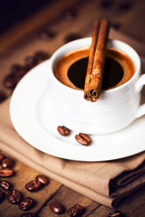 Coffee cup and coffee beans with cinnamon sticks on wooden  brow