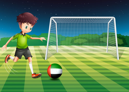 A male athlete kicking the ball with the flag of the United Arab