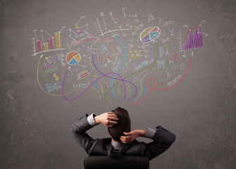 Young business man looking at sketches of graphs and symbols