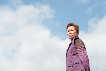 青空をバックに撮影した高齢者の女性