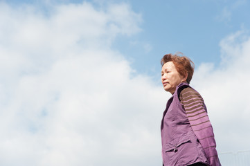 青空をバックに撮影した高齢者の女性