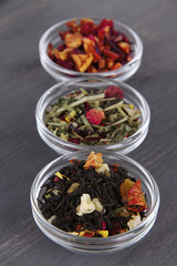 Aromatic dry tea in bowls on wooden background