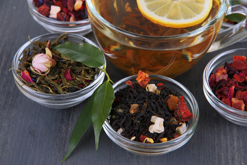 Cup of tea with aromatic dry tea in bowls on wooden background