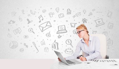 Business woman sitting at table with hand drawn media icons