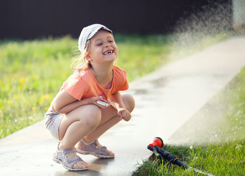 toothless smiling girl watering the grass