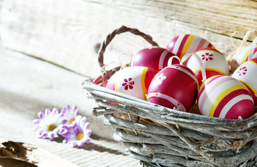 Körbchen mit Ostereiern vor Holzbrett