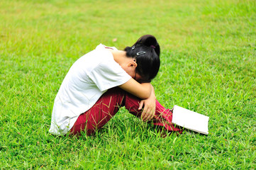 woman college student reading book on green grass