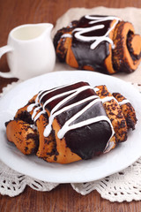 rolls of dough biscuit with poppy seeds and chocolate icing