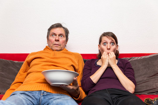 Vater und Tochter sitzen geschockt auf der Couch
