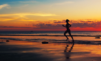 Silhouette of woman runing  along the sea coast