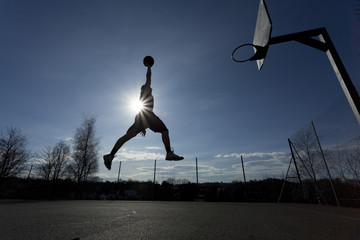 Basketball player silhouette in mid air about to slam dunk