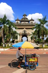 Zelfklevend Fotobehang Street food seller on a bicycle in front of Victory Gate Patuxai © donyanedomam