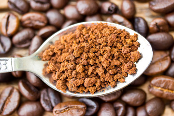 Coffee beans and ground coffee beans on a spoon.