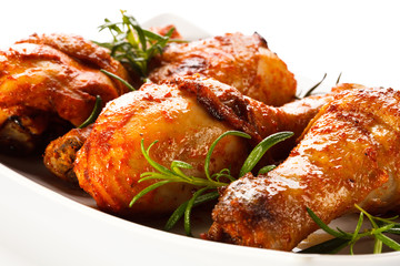 Grilled chicken legs and vegetables on white background