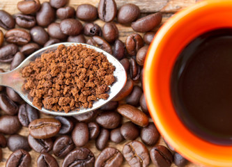 Coffee beans and ground coffee beans on a spoon.