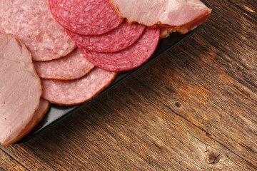 Different salami slices arranged in a black ceramic plate