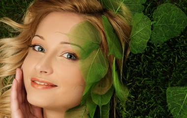 Smiling young woman lying on a fresh spring grass